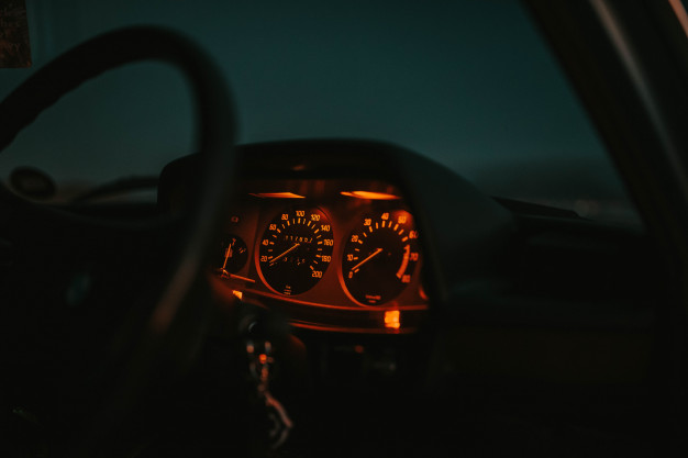car-dashboard-lit-red-with-steering-wheel-night_181624-3294